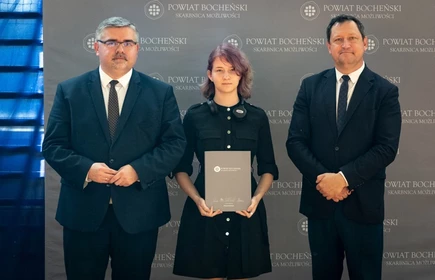 uczeń stojący ze starostą i wicestarostą